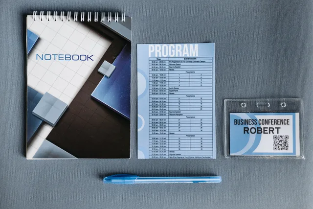 Flatlay of a notebook, conference badge, pen, and program on gray surface. How to run sponsorship rates operations: roles, records and reconciliation