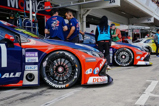 Close-up of colorful race cars in a pit stop with mechanics and crew preparing for a motorsport event. Five weighted criteria for scoring sponsorship rates tools
