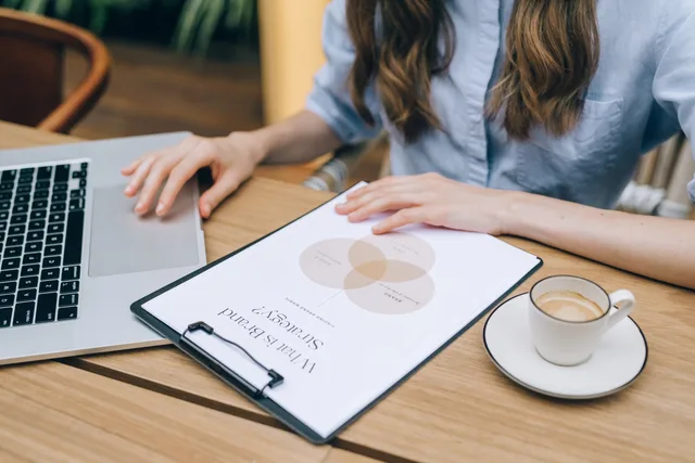 A person reviews a brand strategy document on a clipboard while using a laptop in an office setting. How to build a sponsorship rates quality checklist for brand deals