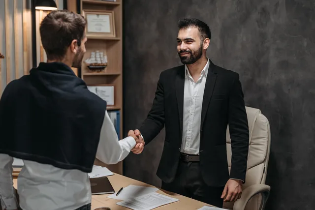Two businessmen shaking hands in a modern office, sealing a business deal. Check sponsorship rates review methodology before you trust a score