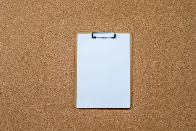 A top-view of a clipboard with blank paper on a cork board, ideal for office and planning concepts. Seven checks to build a sponsorship rates selection checklist
