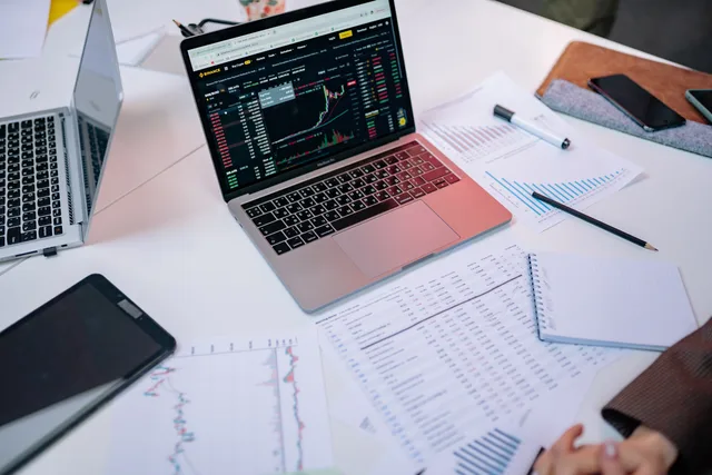 Laptops on a desk displaying stock market charts and financial documents. Buy a rates platform or build your own sponsorship rates software?