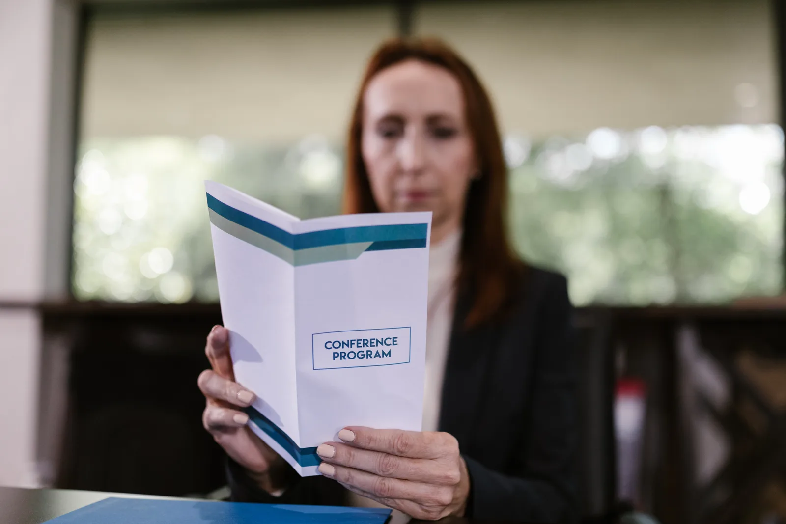 Businesswoman examining the conference program in a meeting room setting.